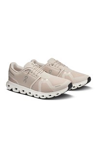 Beige athletic shoes with mesh upper, gray accents, and a white midsole. Features a round toe, lace-up design, and curved tread outsole.