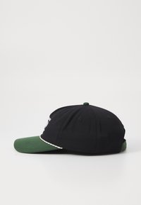 Black cap with a green brim, fitted design, featuring a decorative band along the front edge and embroidered logo details on the side.