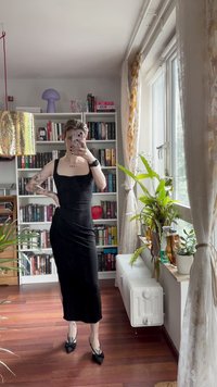 Mustasoppi midi-mekko neliönmuotoisella kaula-aukolla, sileä pinta ja sivureikä. Yhdistetty mustiin korkokenkiin, joissa on nauhat. Sisätila, jossa on kirjahyllyjä.
