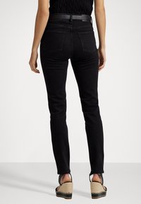 Zwarte skinny jeans met een normale taille, voorzien van twee achterzakken, gecombineerd met wedge sandalen met een gestructureerd strooiplatform en leren band.