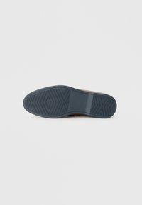 Suela de zapato marrón con un agarre de goma texturizada, que presenta una capa inferior azul y un patrón de espiga para tracción.