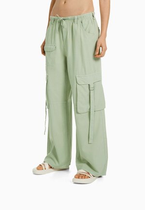 Ljusgröna cargobyxor med elastiskt midjeband, flera fickor och dragsko-detalj. Tillverkade av mjukt tyg och har en avslappnad passform.