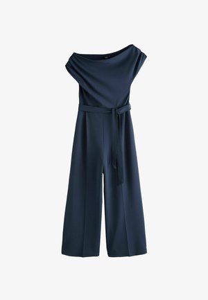 Laajalahkeinen laivastonsininen haalari, jossa olkapäät paljastava pääntie, poimutetut hihat ja vyötäröllä solmittava kangasvyö.