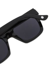 Černé sluneční brýle s velkými, obdélníkovými skly a lesklým povrchem. Vybavení zahrnuje štíhlé nožičky s bílým tečkovaným akcentem poblíž pantů.