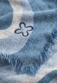 Scarf blu e grigio a motivi con bordi frangiati, caratterizzato da una superficie liscia e un dettaglio di fiore ricamato in blu scuro.