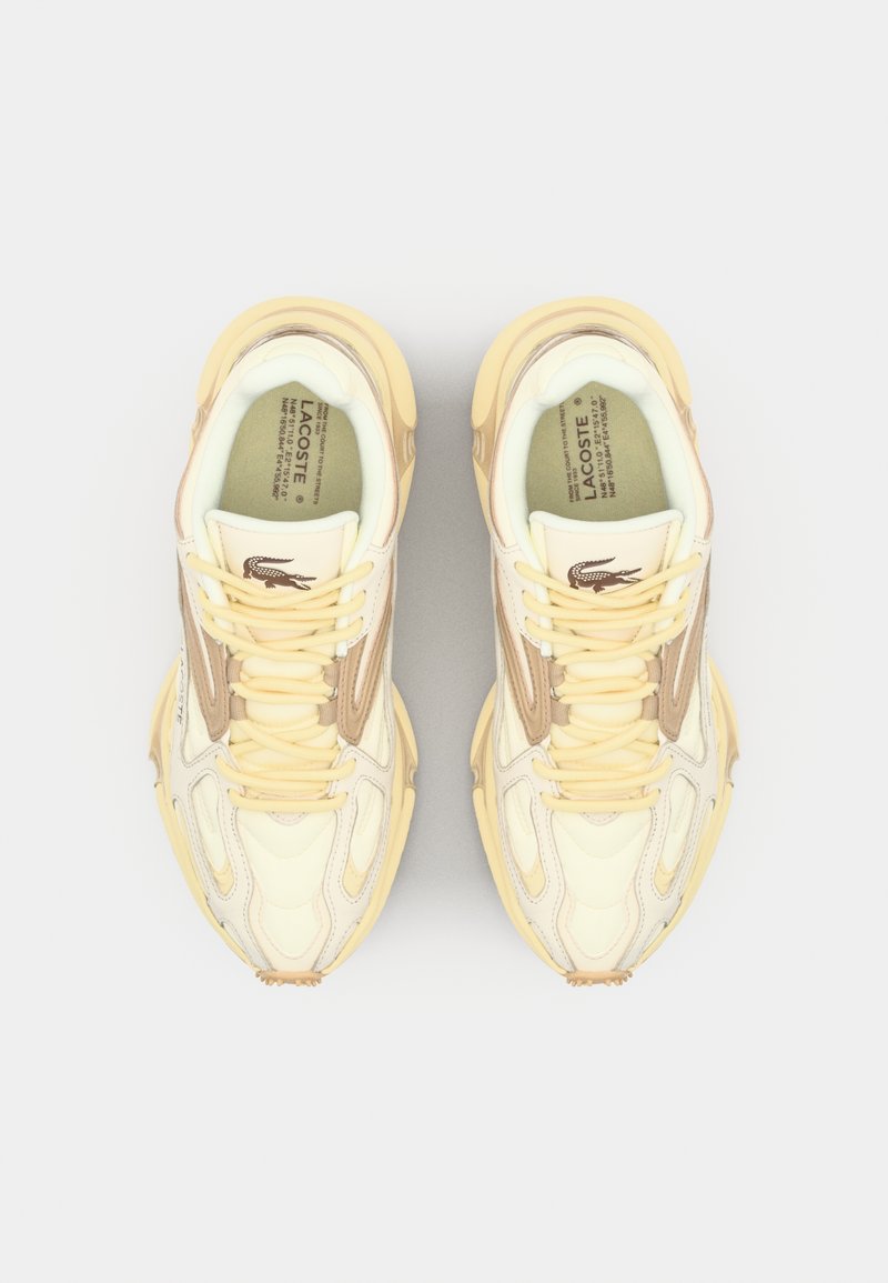 Sneakers Lacoste w jasnym żółtym kolorze, z beżowymi akcentami, teksturowana cholewka, z wyraźnym sznurowaniem i detalem logo na języku.