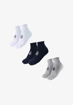 Tre paia di calzini alla caviglia in bianco, nero e grigio, ciascuno con un piccolo logo circolare ricamato vicino alla caviglia.