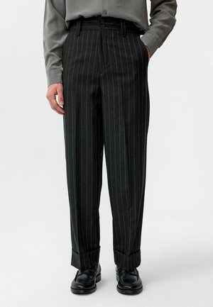 Op maat gemaakte zwarte pantalon met pinstripes, een hoge taille, zijzakken en manchetten. Gemaakt van een gladde stof met een klassieke pasvorm.