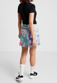 Colorful, patterned skirt with paisley design in green, pink, and blue; made from lightweight fabric, features a fitted waist and flared hem.