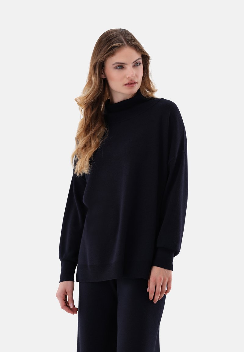 Navyblauer, übergroßer Pullover mit hohem Ausschnitt, langen Ärmeln und gerippten Bündchen, aus einem weichen Stoff mit glatter Textur.