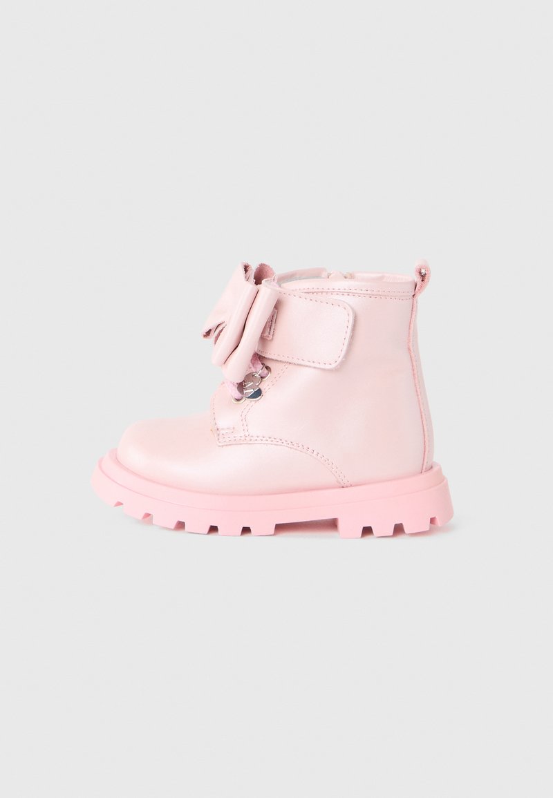Botte bi-matière en cuir rose, avec une surface texturée, un bout arrondi, une bande Velcro et un nœud décoratif. Semelle épaisse rose avec un motif de traction.