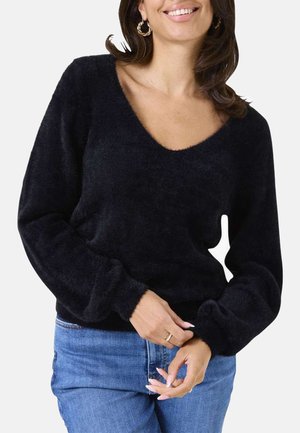 Schwarzer, flauschiger Pullover mit V-Ausschnitt und langen, weiten Ärmeln. Weiche Textur, tailliert, getragen über hellblauen Jeans.