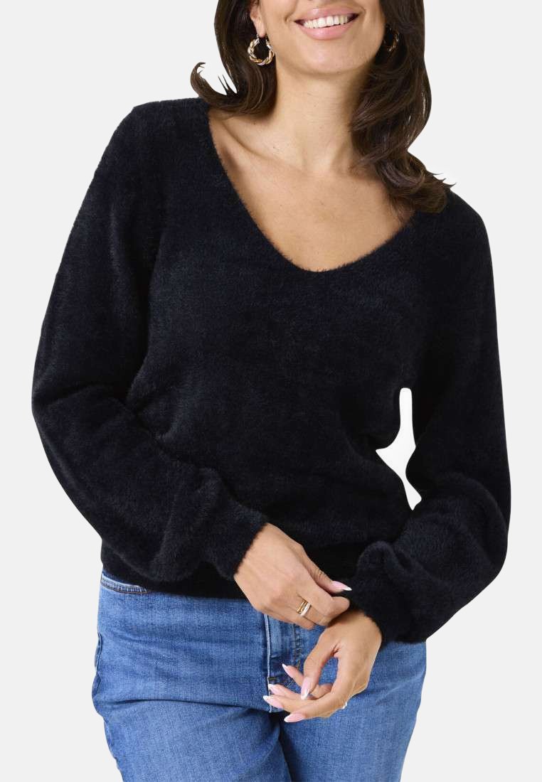Schwarzer, flauschiger Pullover mit V-Ausschnitt und langen, weiten Ärmeln. Weiche Textur, tailliert, getragen über hellblauen Jeans.