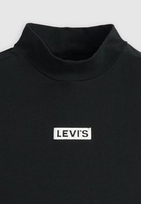 Crna majica s visokim ovratnikom izrađena od glatke tkanine, sa bijelim pravokutnim Levi's logom na prednjoj strani. Dostupna u uskom kroju.
