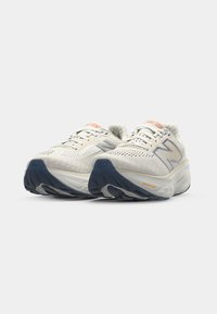 Chaussures de course blanches avec une tige en mesh, accents gris et une semelle en caoutchouc bleue. Présente des marques "Fresh Foam" et un design texturé.