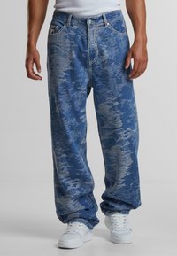 Blue denim jeans with a faded, textured pattern, featuring a relaxed fit, contrasting stitching, and classic five-pocket design.