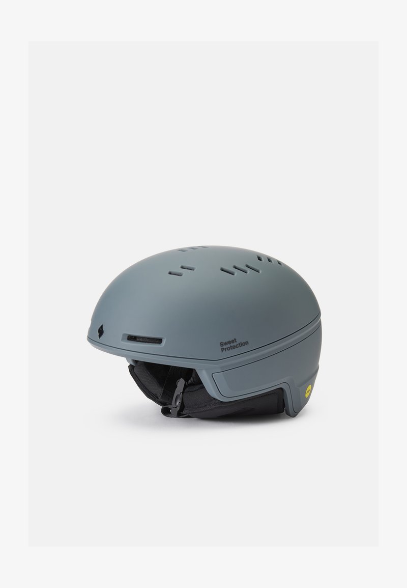 Casco duro gris con ranuras de ventilación, correa para la barbilla ajustable y un interior acolchado. Presenta un logotipo y el sistema MIPS para mayor seguridad.