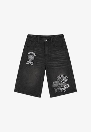 Short en jean noir avec boutons à l'avant, deux poches, et des imprimés graphiques blancs incluant des crânes, du texte, et "EST 1971" sur chaque jambe.