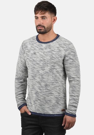 Hellgrauer strukturierter Pullover mit rundem Halsausschnitt, mit marineblauen Akzenten am Kragen und an den Bündchen. Dezentes Muster über die gesamte Oberfläche.