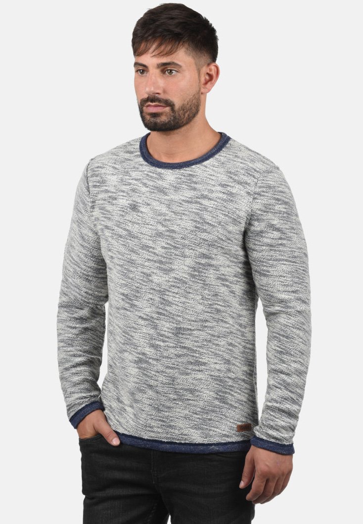 Lys grå teksturert genser med rund hals, med marineblå detaljer på kragen og mansjettene. Subtilt mønster gjennom hele.