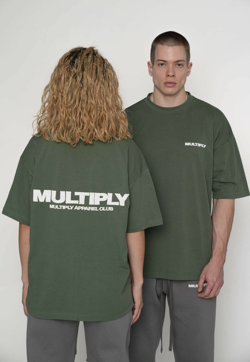 Grønne bomulds t-shirts med hvidt "MULTIPLY" logo på ryggen og brystet. Oversized pasform, korte ærmer, kombineret med grå joggingbukser.