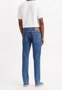 Blå denimjeans med rak passform, med en märkesläderlapp på baksidan, djupa fickor och en medeltvättad finish.