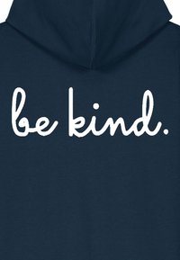 Hanorac cu glugă de culoare bleumarin, având un text mare, alb, scris de mână "fii bun" pe spate. Material moale, cu o textură netedă.