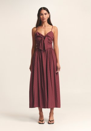 Bordowa sukienka maxi w białe kropki, z przodem ozdobionym kokardką, regulowanymi ramiączkami i zwiewną spódnicą.