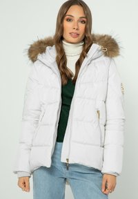 Přefoukaná bunda světle šed�é barvy s odnímatelnou kapucí s kožešinovým lemem, kapsami na zip a zlatými kovovými detaily. Vyznačuje se prošívanou texturou.