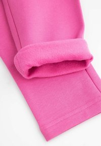 Legginsy z różowej bawełny wyłożone polarem, z zawiniętym mankietem, gładką fakturą i przeszytymi szwami dla zwiększenia trwałości.