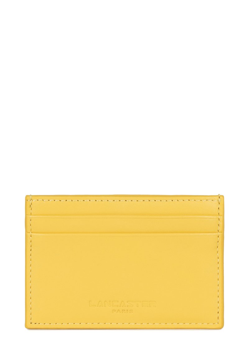 Porte-cartes en cuir jaune avec plusieurs fentes pour cartes, coutures visibles et logo de la marque embossé en bas. Texture lisse.