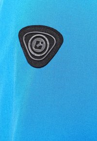 Een close-up van een heldere blauwe stof met een getextureerd zwart driehoekig stuk met een circulair logo, gestikt voor duurzaamheid.