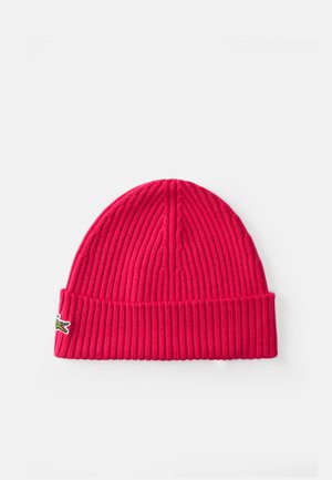 Knitted red beanie with a ribbed texture and folded brim. Features a small embroidered crocodile logo.