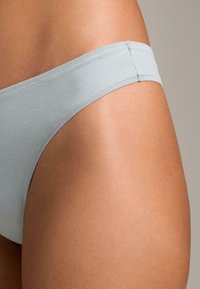 Hellblaue Bikini-Hose aus einem glatten, dehnbaren Stoff. Sie verfügt über ein tief sitzendes Design und minimale Nähte entlang des Bundes.