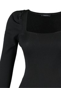 Zwarte top met lange mouwen en een vierkante halslijn, geribbelde textuur en zachte stof. Heeft subtiele plooitjes bij de schouder voor extra vorm.