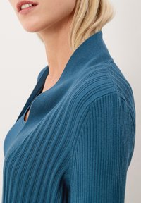 Ribbade stickade tröja i teal med en bred krage, med vertikala ränder och en figurnära design, som visar en mjuk textur.