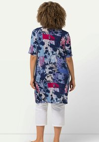 Modré a fialové tunice s krátkým rukávem, zdobené květinovými a geometrickými vzory, v kombinaci s bílými zkrácenými kalhotami.