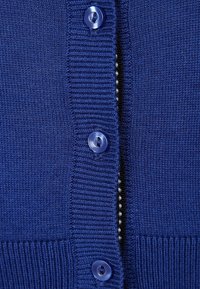 Modrý pletený kardigan s žebrovanou strukturou, pěti velkými kulatými knoflíky a kontrastní podšívkou se zapínáním na knoflík.