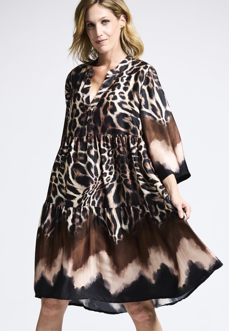 Leopardenmuster Kleid aus seidig glänzendem Stoff mit tiefem V-Ausschnitt, langen Ärmeln und gerafftem Rock. Braune und schwarze Farbtöne erzeugen einen Übergangseffekt.