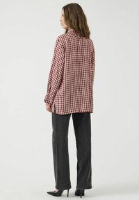 Rood-wit geruit overhemd met een afgeronde zoom, gecombineerd met donkergrijs rechte broek en zwarte hakken.