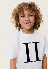 Λευκό βαμβακερό t-shirt με σκούρα μπλε γράμματα μπλοκ "II" στο μπροστινό μέρος. Με κοντά μανίκια και στρογγυλή λαιμόκοψη.