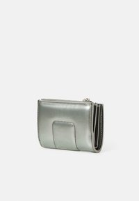 Metalen zilveren portemonnee met een minimalistisch ontwerp, voorzien van een ritsluiting, gestikte details en een voorzakaccent voor kaarten.