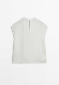 Blouse blanche sans manches avec un col montant et une ouverture en forme de trou de serrure dans le dos, fermée par un petit bouton.