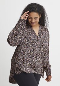 Garums piedurkņu melna blūze ar ziedu rakstu rozā un dzeltenā krāsā, ar V-veida izgriezumu, brīvu piegriezumu un sānu šķēlumiem gaisa plūsmai.