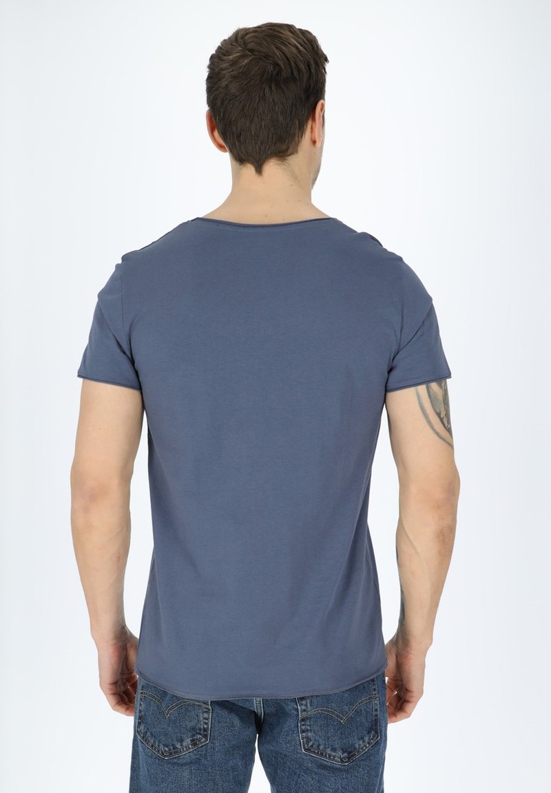 T-shirt in cotone blu con scollo rotondo e maniche corte, caratterizzato da un design semplice e una silhouette aderente, abbinato a jeans in denim.