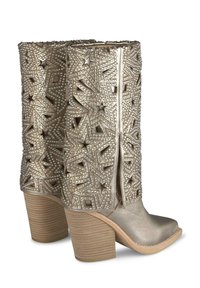 Metallisch goldene Knöchelstiefel verfügen über ausgeschnittene Sternmuster und genietete Akzente, mit einem geschwungenen Absatz und einer glatten Textur.