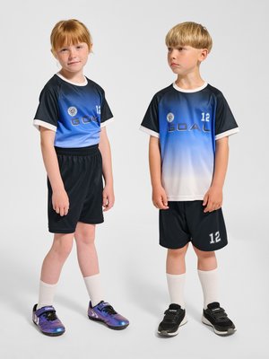 To børn i matchende blå og sorte fodbolduniformer med nummer 12, stående side om side på en ensfarvet baggrund.