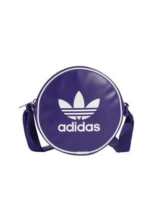 Kulatá fialová taška přes rameno Adidas s bílým logem trefoil a nastavitelným popruhem na bílém pozadí.