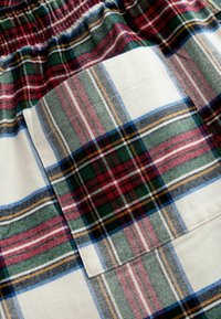 Shorts cu carouri, cu o talie elastică, având un amestec de modele verzi, roșii și albe. Include un buzunar din țesătură cu design în carouri.
