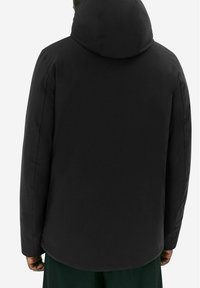 Černá kapuce bunda s hladkým, voděodolným povrchem, volným střihem a zaobleným lemem. Minimalistický design bez viditelných zapínání.